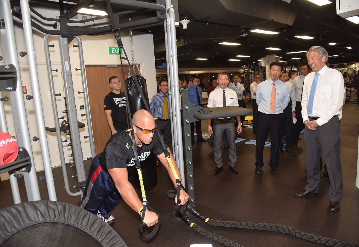 SAFRA EnergyOne gym trainer demonstrating use of suspension cable workout to DPM Teo Chee Hean, Mr Ong Ye Kung and other guests.